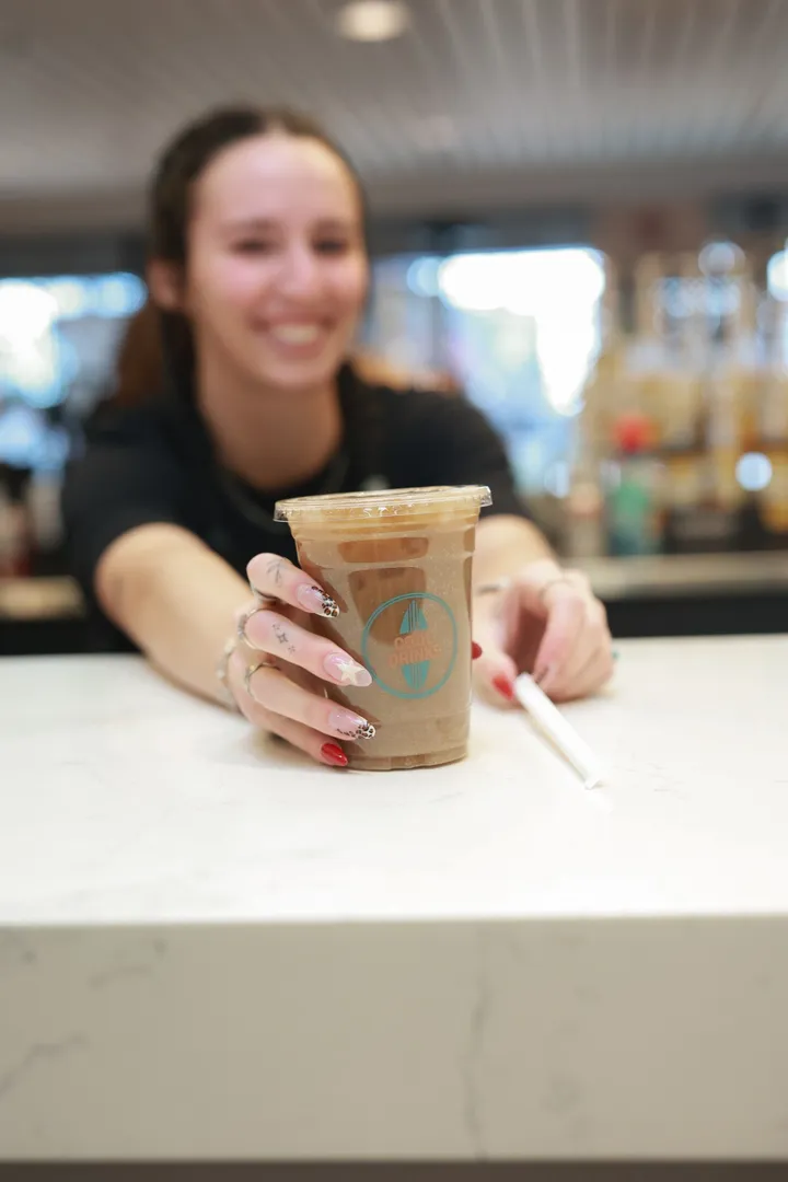 A smiling team member sliding a Cool Drinks iced drink across the counter