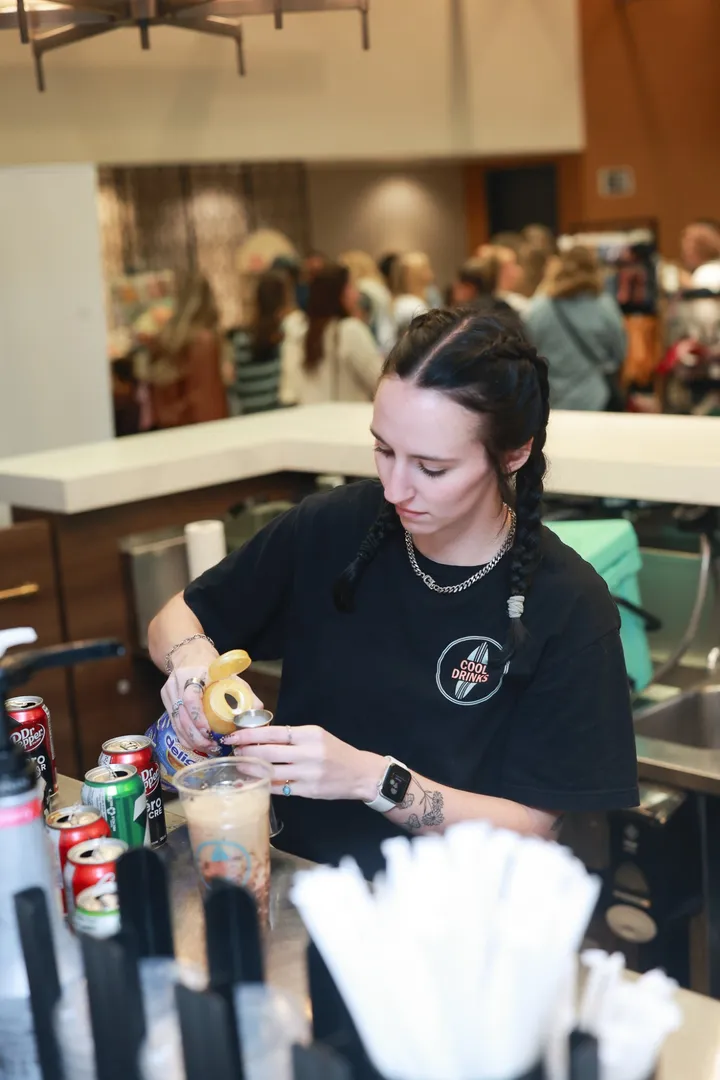 A team member pouring syrup into a dirty soda at a busy event