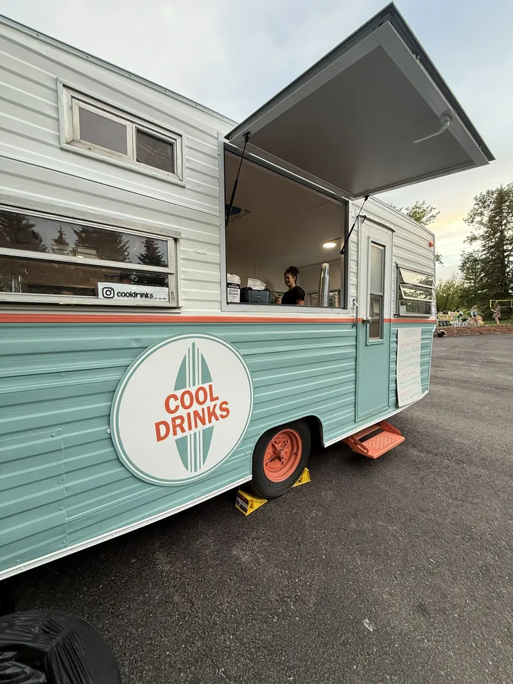 The Cool Drinks trailer set up at dusk with its serving window propped open