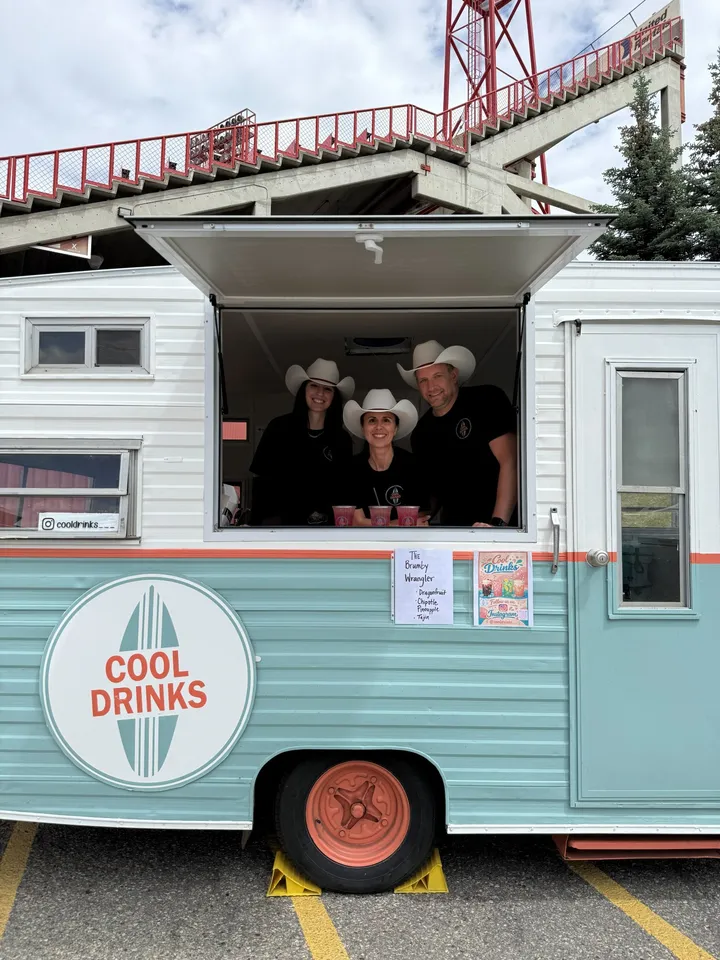 Three team members in cowboy hats serving from the Cool Drinks trailer at a Stampede event