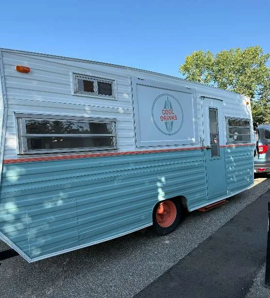 The Cool Drinks vintage teal and white catering trailer with the surfboard logo on its side
